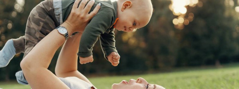 maman allongée dans l'herbe soulevant son bébé