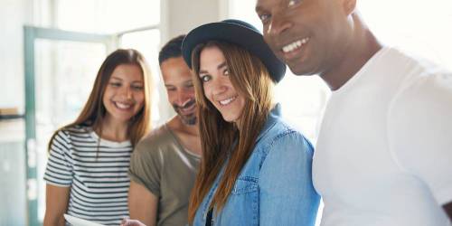 Jeune équipe de startup, deux hommes, deux femmes, cherchent des solutions de financement professionnel sur leur tablette.