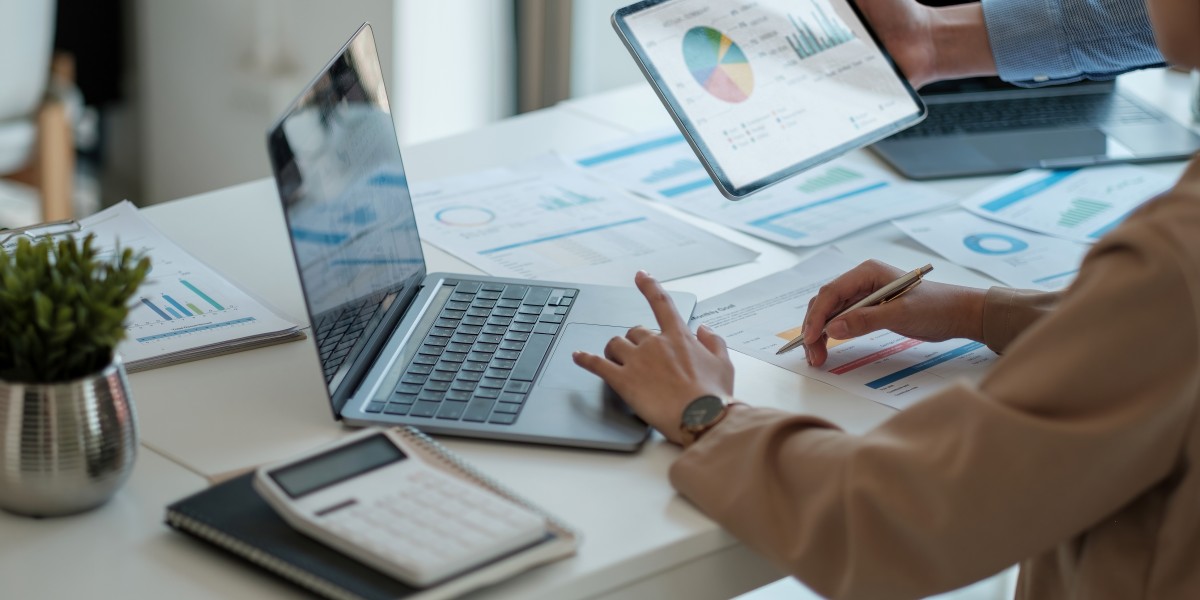 Deux professionnels analysant des graphiques financiers sur une tablette et un ordinateur pour élaborer un business plan.