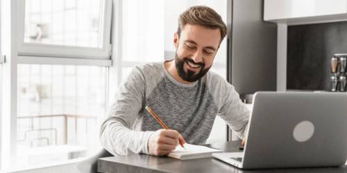 Jeune homme devant son ordinateur portable calculant sa capacité d'emprunt