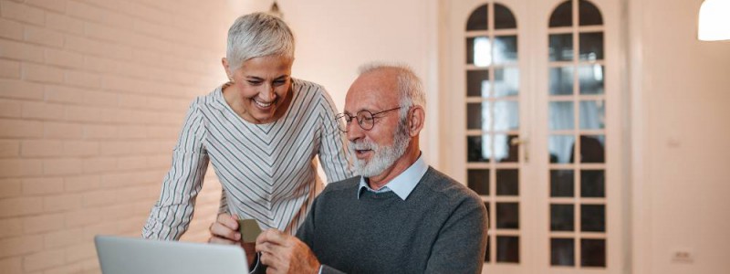 Deux personnes de plus de soixante ans devant leur ordinateur portable heureux de leur banque en ligne