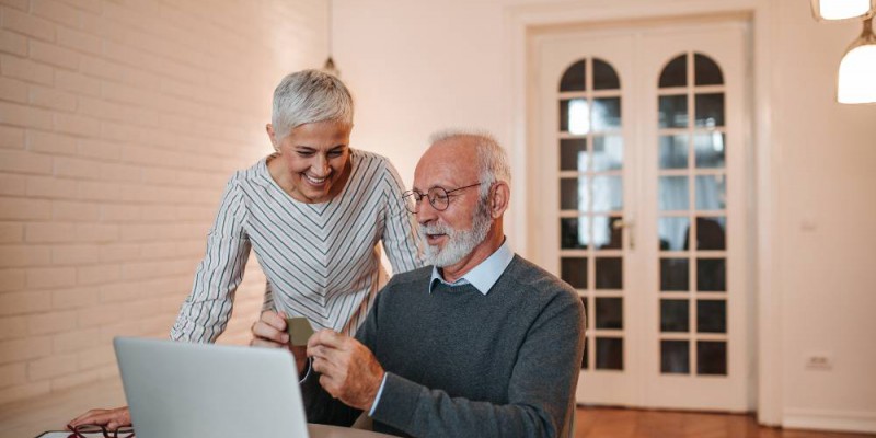 Deux personnes de plus de soixante ans devant leur ordinateur portable heureux de leur banque en ligne