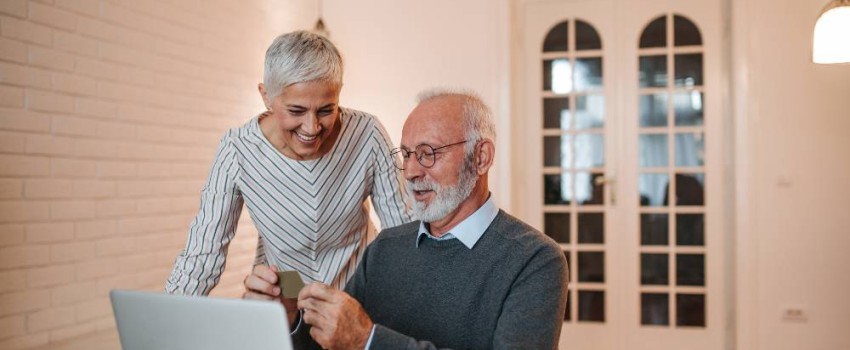 Deux personnes de plus de soixante ans devant leur ordinateur portable heureux de leur banque en ligne
