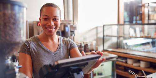 gérante d'un café souriante derrière comptoir