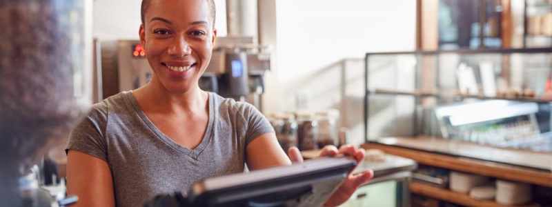 gérante d'un café souriante derrière comptoir