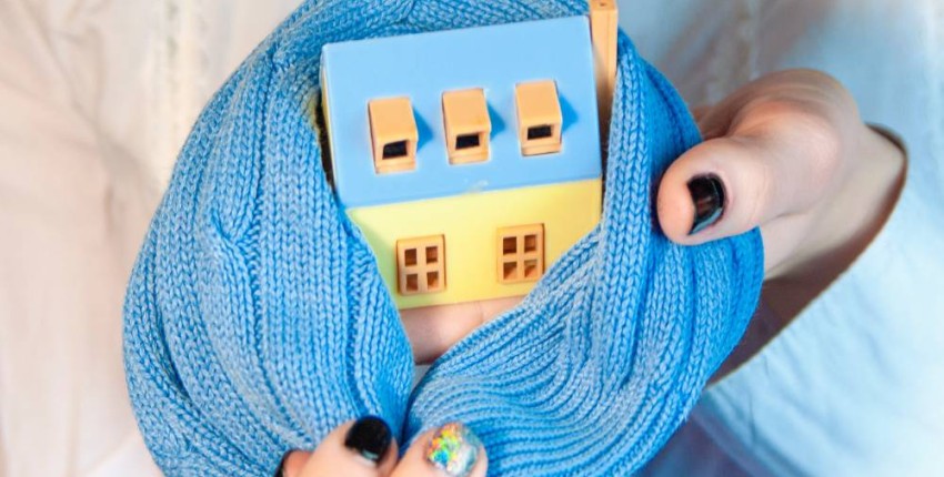 Maison en bois miniature avec une petite écharpe bleue entre les mains d'une femme