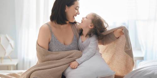mère et fille jouant dans le lit au matin