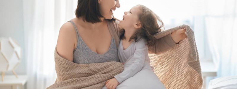 mère et fille jouant dans le lit au matin