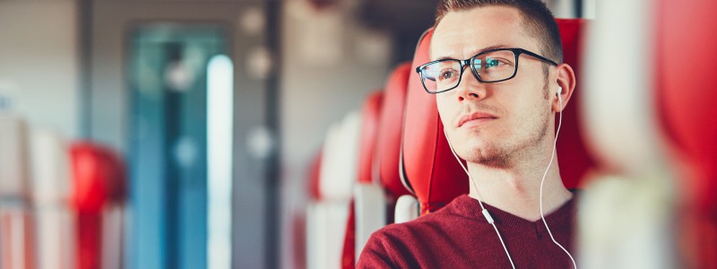 Un étudiant est assit dans le train et attend une réponse pour savoir si son prêt étudiant peut faire office à un rachat de crédits