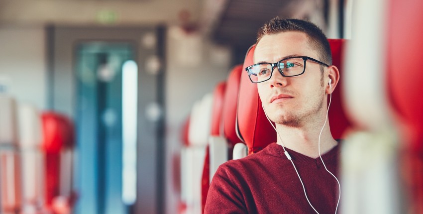 Un étudiant est assit dans le train et attend une réponse pour savoir si son prêt étudiant peut faire office à un rachat de crédits