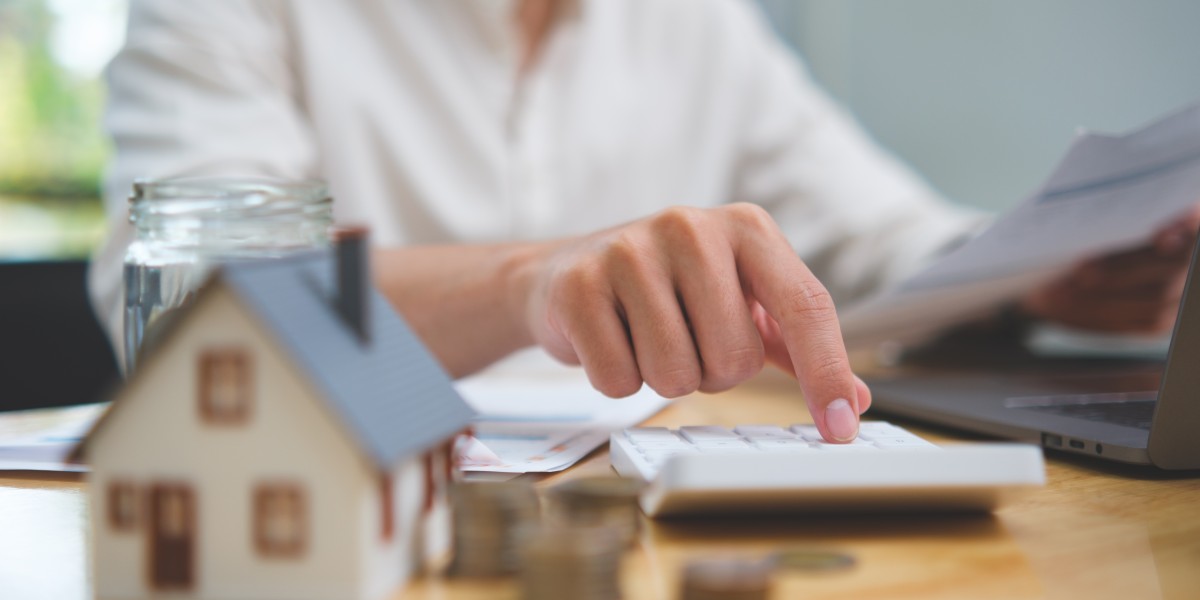 Analyse d'un exemple de rachat de crédit propriétaire : une personne utilise une calculatrice à côté d'une maquette de maison.