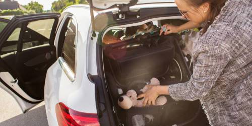 Femme chargeant la nouvelle voiture avec sac et doudous des enfants