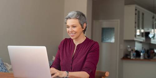 Une femme est devant son ordinateur et fait une demande pour racheter son rachat de crédits