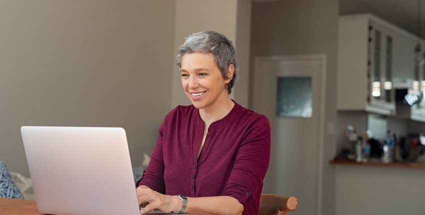 Une femme est devant son ordinateur et fait une demande pour racheter son rachat de crédits
