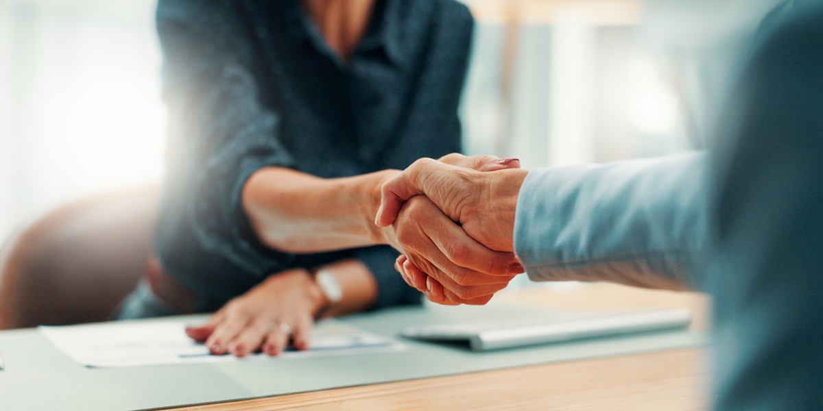 Poignée de main professionnelle scellant un accord de financement d'entreprise après la signature de documents sur un bureau.
