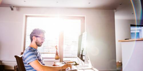 homme assit seul à son bureau devant son ordinateur fait une demande de rachat de crédits