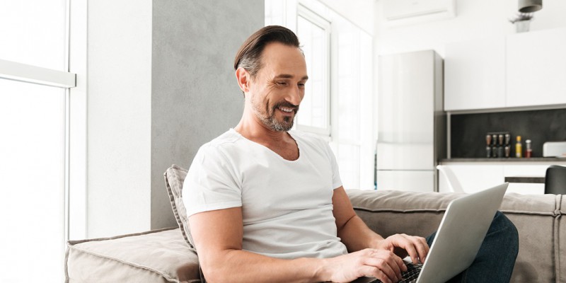 homme assit devant ordinateur content grâce à un rachat de crédits