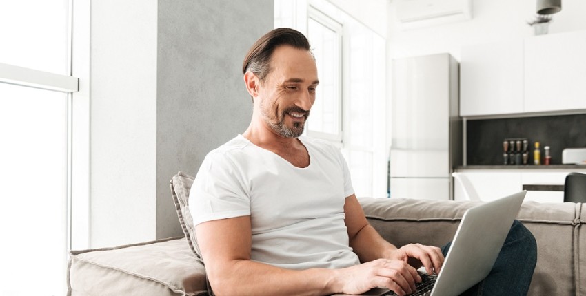 homme assit devant ordinateur content grâce à un rachat de crédits