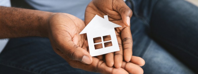 homme tenant une petite maison en carton entre ses mains