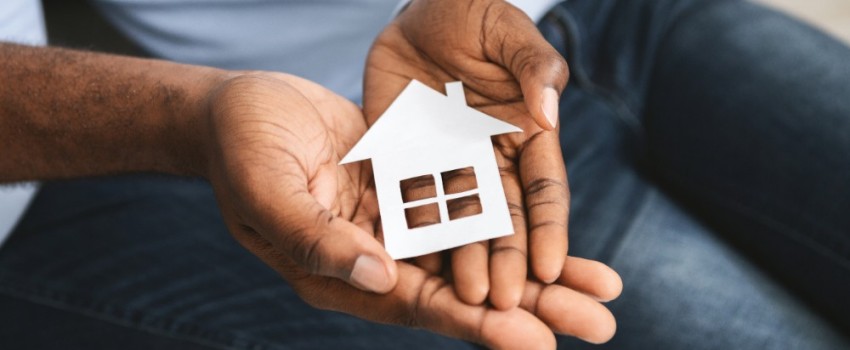 homme tenant une petite maison en carton entre ses mains