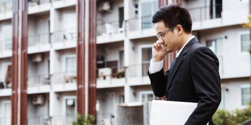 Homme au téléphone devant un immeuble composé d'appartements
