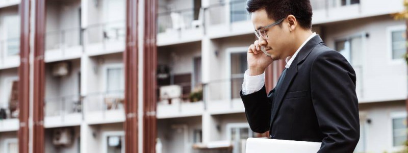 Homme au téléphone devant un immeuble composé d'appartements