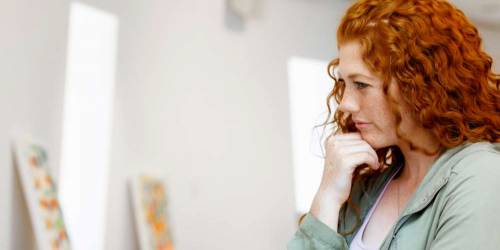 Jeune femme rousse réflechissant dans une galerie d'art
