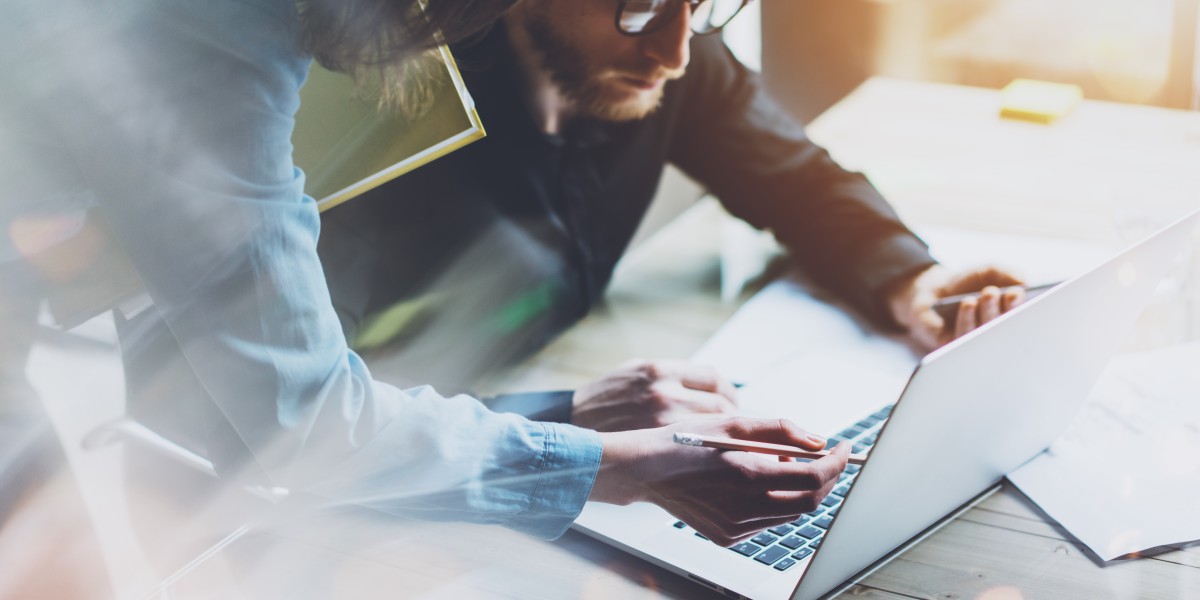 Deux entrepreneurs travaillant ensemble sur un ordinateur portable pour analyser et structurer le business model de leur projet professionnel.