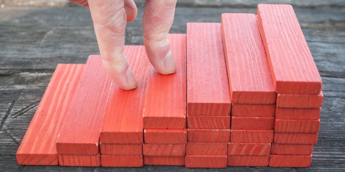 Doigts gravissant des marches en bois rouge, symbolisant la progression pas à pas dans les étapes d'un rachat de crédits.