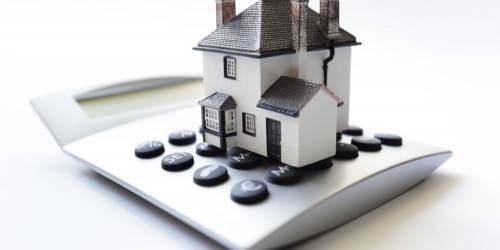 Maison posée sur une calculatrice pour la taxe foncière