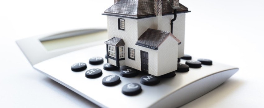 Maison posée sur une calculatrice pour la taxe foncière