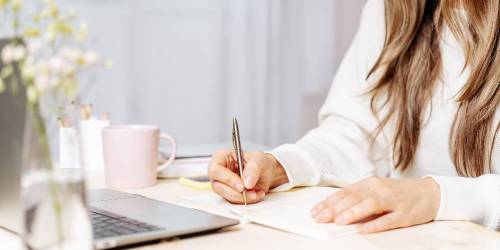 femme prenant des notes devant son ordinateur