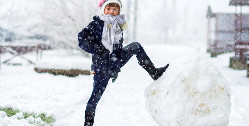 enfant fier devant son énorme boule de neige