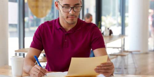 jeune homme à lunettes calculant ses indemnités de remboursement anticipé