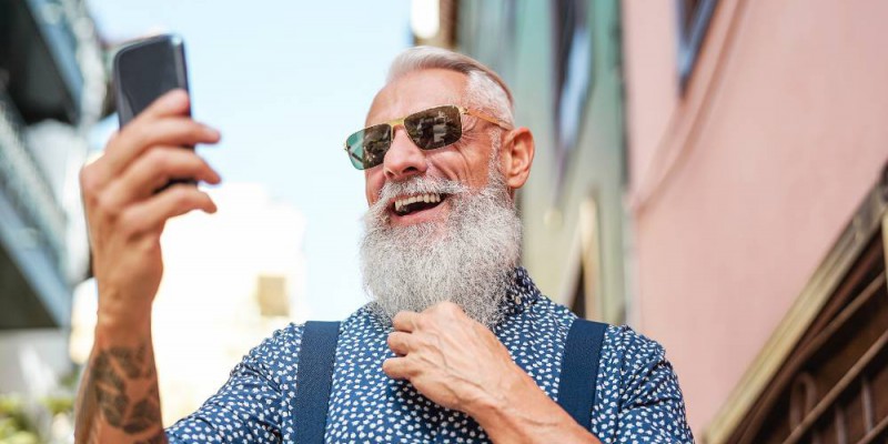 Homme âgé et barbu regardant son smartphone