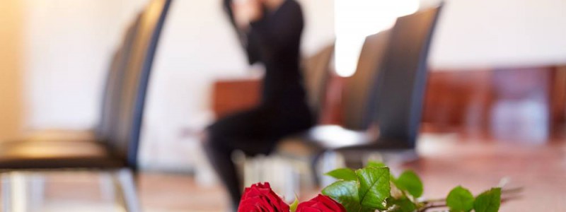 Roses rouges posées sur meuble en bois dans un funérarium.