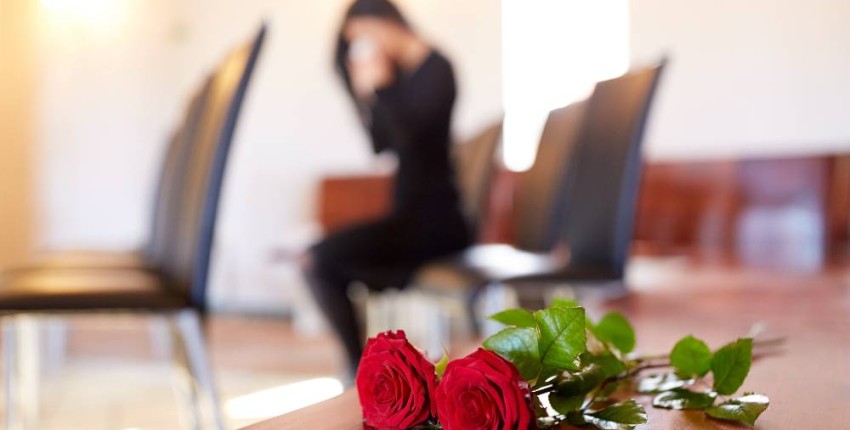 Roses rouges posées sur meuble en bois dans un funérarium.