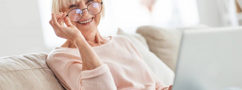 femme assise dans son canapé son ordi portable sur les genoux