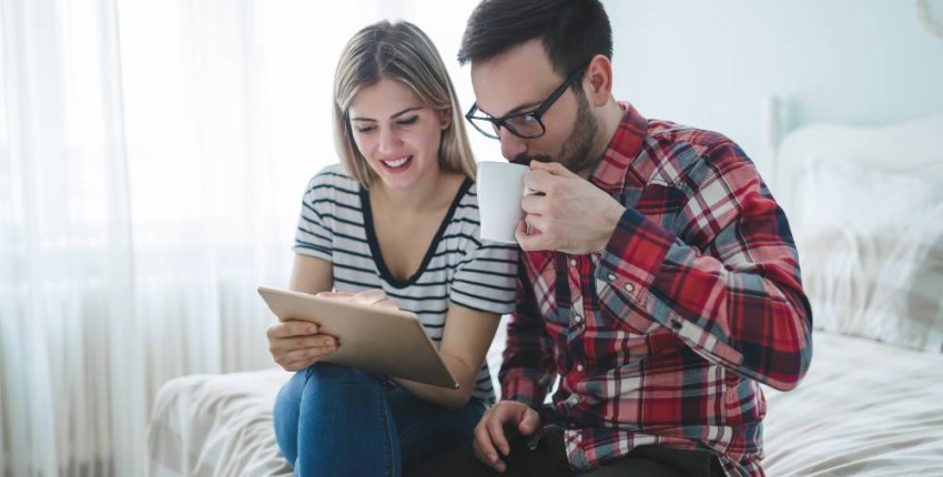 couple se renseignant sur l'estimation du bien immobilier à acquérir sur une tablette