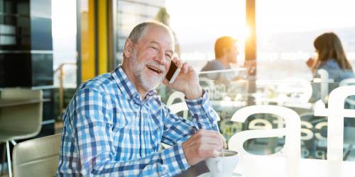 Retraité prenant un café et heureux d'apprendre que sa demande de rachat de crédits a été acceptée.