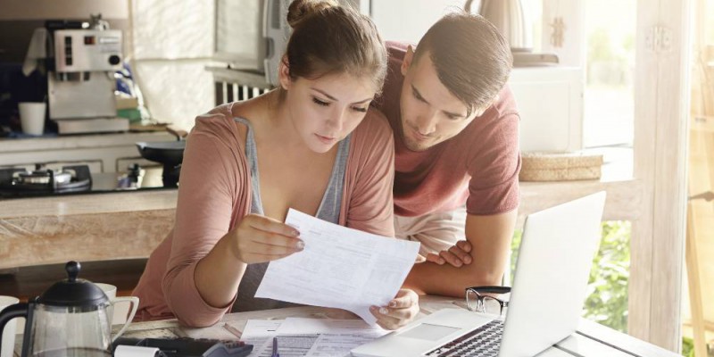 couple faisant le calcul de sa capacité d'emprunt sur un ordinateur portable dans la cuisine